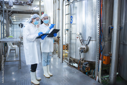Schilderij op canvas Female engineers inspecting industrial storage tank and piping system in a facto