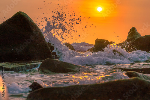 Wallpaper Mural Sunrise landscape at tropical beach. The warm golden light of illuminating the sea spray creates a striking silhouette of the rocks against the glowing sky Torontodigital.ca
