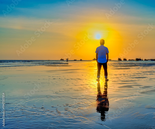 Wallpaper Mural The silhouette of a man stands alone on a wide sandy beach while watching a vibrant sunset over the ocean. Torontodigital.ca