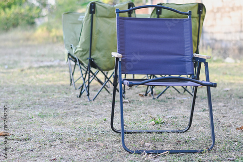 Fotografia Folding camping chairs set up on dry grass outdoors.