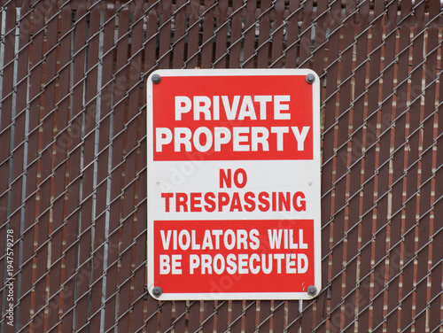 Red and white sign that says private property, no trespassing, and violators will be prosecuted