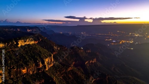 Deep canyons under twilight sky, distant city lights glow dimly