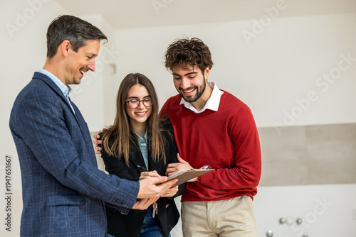 Fotografie Young couple signing a real estate contract for a new apartment with an agent