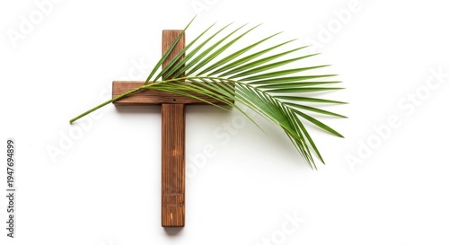 Wooden christian cross with green palm branch isolated on white background. Symbol for Palm Sunday. Traditional religious icon representing faith, peace and resurrection during Easter.