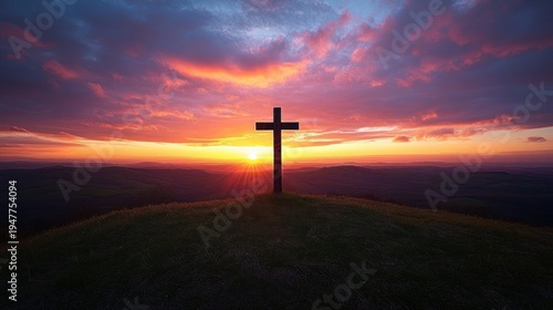 Silhouetted wooden cross on a grassy hilltop at sunrise with radiant sun rays and colorful dramatic clouds over rolling countryside — peaceful, hopeful, contemplative scene