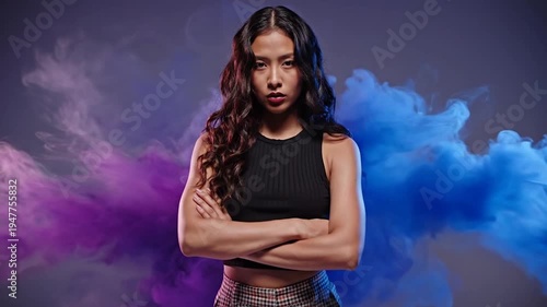 A young woman of Latin American ethnicity with arms crossed and an intense stare, surrounded by dramatic clouds of purple and blue smoke
