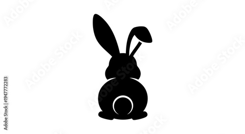Black silhouette of a rabbit with long ears and a fluffy tail facing away.