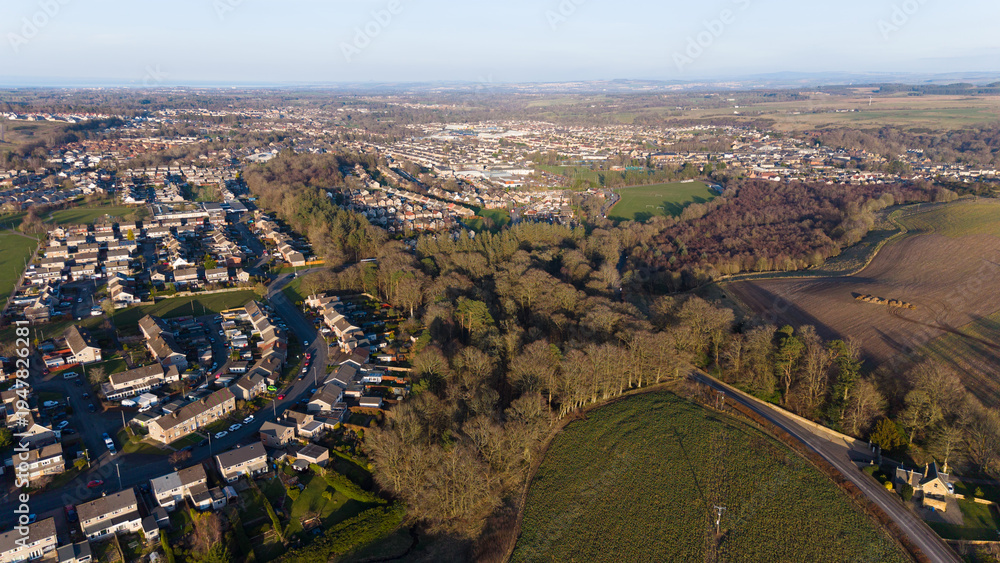 Fototapeta premium Aerial view of Penicuik nestled in lush greenery: A scenic Scottish townscape surrounded by vibrant fields and woodland in Midlothian