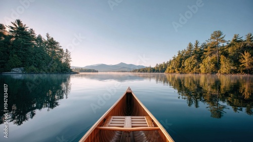 Canoe on a calm lake at sunrise with forest reflections