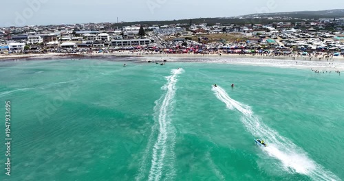 Drone aerial view of competitors racing inflatable boats during the Trans Agulhas Challengealong the turquoise coastline of Struisbaai in the Western Cape, South Africa.