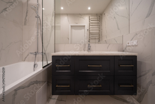 Modern bathroom with dark blue vanity and marble tiling