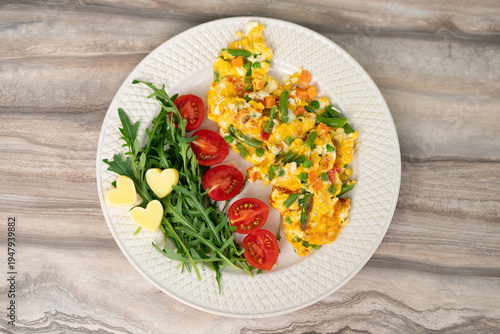 Scrambled eggs with vegetables served with arugula and cherry tomatoes