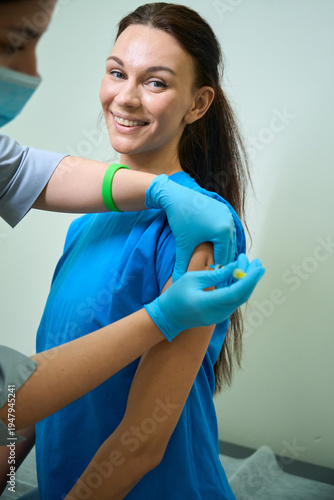 Young Caucasian woman smiling while receiving vaccination indoors