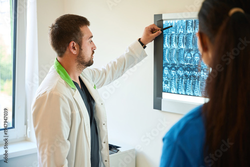 Male doctor showing spinal x-ray to female patient indoors