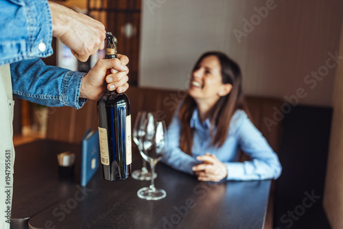 Waiter Opening Wine Bottle for Smiling Woman at Restaurant Table During Casual Dinner Service