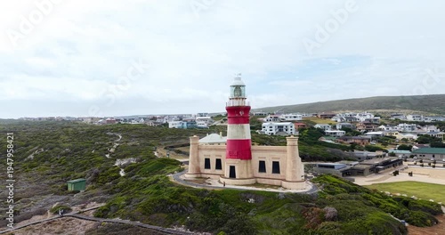Drone aerial view of Cape Agulhas Lighthouse overlooking coastal fynbos and the seaside town at the southernmost tip of Africa in the Western Cape, South Africa.