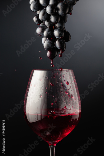 Red wine flows down the grape cluster into the glass.