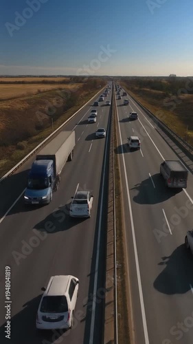 Vehicles driving on a multi-lane highway with grassy median on a sunny day