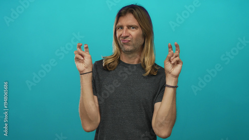 Obraz na plátne Man with long blond hair making finger quotes gesture with both hands and a skeptical expression in a studio; skepticism humor