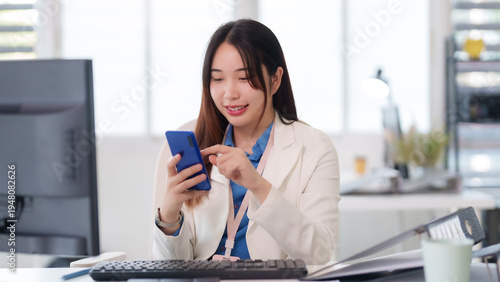 Asian business professional using smartphone digital communication social media modern office environment desk workspace