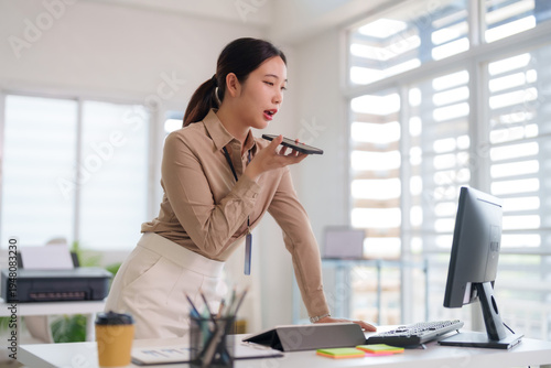 Konstfotografi Asian business professional woman uses voice command smartphone dictating messag