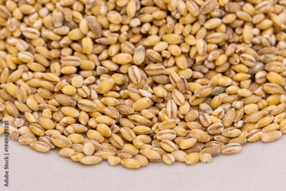 Fototapeta premium Pearl barley grains textured background. Close-up. Macro. Raw peeled cereal pattern, organic pearl barley wallpaper.