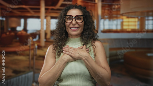 Canvastavla Woman pointing finger in hotel lounge with open palms and bright smile against plush couches and ambient lighting; hospitality