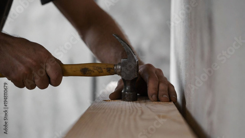 Close-up of hands holding a hammer and lightly tapping a wooden surface in a minimal scene, with soft lighting and realistic textures creating a calm, detailed visual