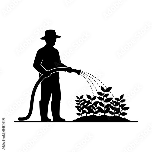 Silhouette of a person in a hat and boots watering plants with a garden hose.