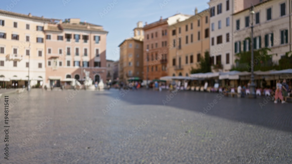 Obraz premium Defocused sunlit plaza scene with soft bokeh over cobblestone square and historic facades; backplate copyspace backdrop calm.