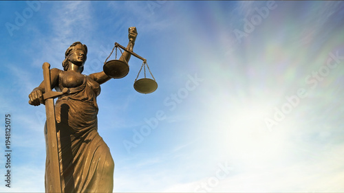 Lady Justice Statue Low Angle View with Sunlight Flare Against Blue Sky