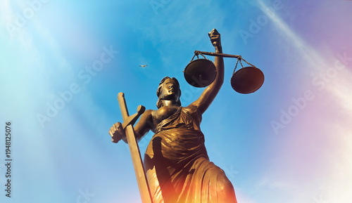Foto Lady Justice Statue Low Angle View with Sunlight Flare Against Blue Sky