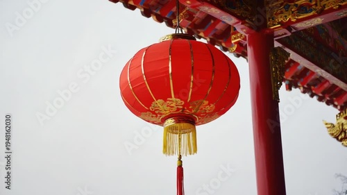 Vibrant red lantern hanging against a traditional wall, casting warm light in a serene courtyard