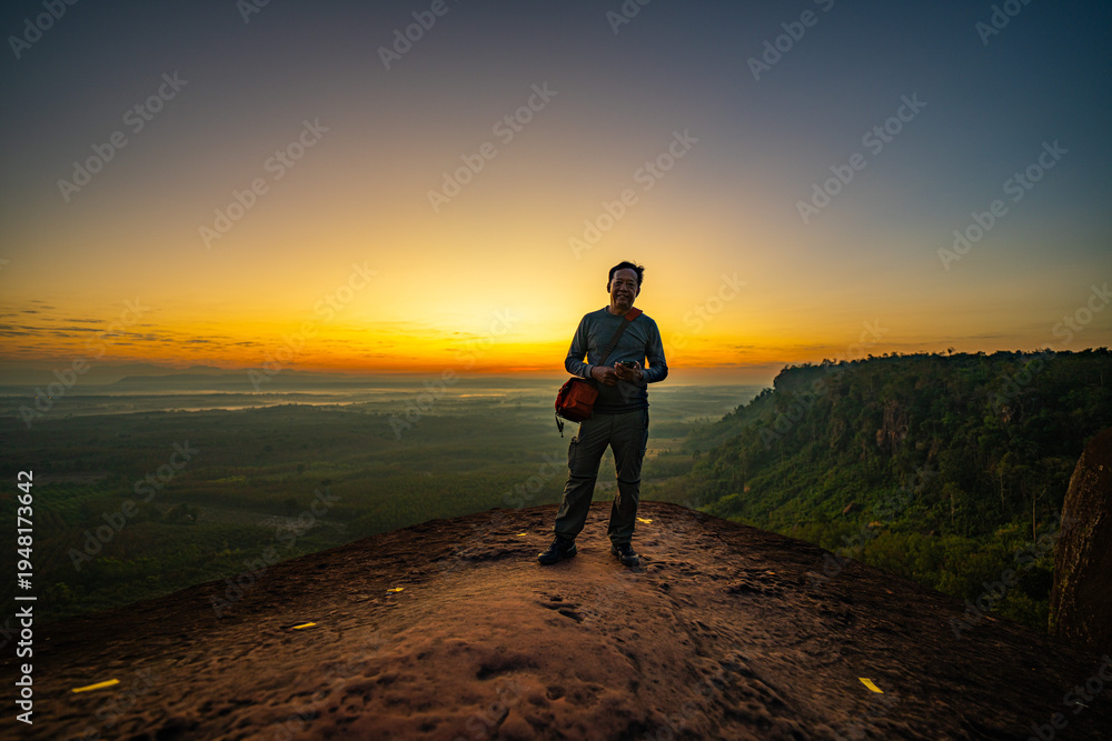 Obraz premium Bueng Kan, Thailand. 02 December 2025; Three Whale Rock Iconic Viewpoint of Northeastern Thailand. Epic sunrise at a famous Thai viewpoint, capturing tiny human figures on a colossal rock ledge
