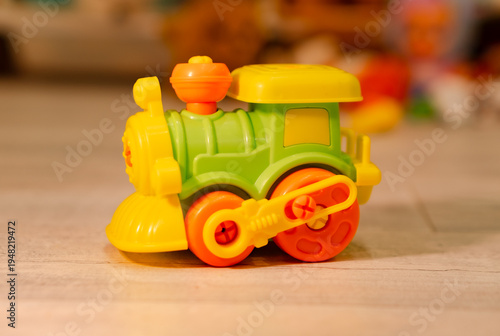 Small plastic toy train on floor. Colorful toddler engine model for imaginative play. Childhood development object for nursery school and home activity. Cute miniature transport vehicle.