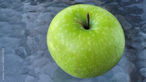 a large green apple on a glass tabletop