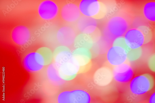 Abstract multicolored bokeh light circles softly blurred over a bright red background, creating a vibrant festive atmosphere.