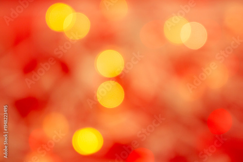 Abstract warm golden bokeh light circles softly blurred on a vibrant red background, creating a festive and glowing atmosphere.