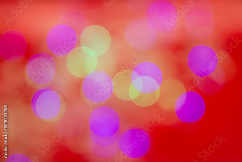 Soft multicolored bokeh light circles blurred over a vibrant red background, creating a festive and dreamy abstract atmosphere.