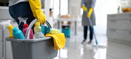 The Cleaning Caddy Filled with Supplies in Bright Modern Kitchen While Worker Mops