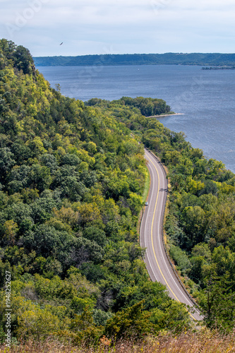 Winding Great River Road (Highway 35) along Maiden Rock Bluff, Wisconsin, with green forest, river, sandy bend, and scenic natural landscape.
