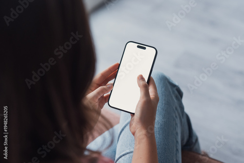 Close up of female hands holding phone with white blank space. Woman using phone in office with laptop on the background. Shopping online insurance concept