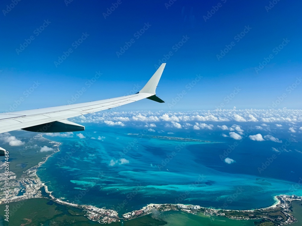 Fototapeta premium Window view of airplane wing above Mexican coastline including Cancun hotel zone and Isla Mujeres in Quintana Roo, Yucatan Peninsula, Mexico