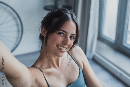 Smiling young woman on a yoga mat indoors, holding her smartphone to record a personal POV shot, combining mindfulness, yoga practice, and sharing her healthy lifestyle digitally Free Download Smiling young woman on a yoga mat indoors, holding her smartphone to record a personal POV shot, combining mindfulness, yoga practice, and sharing her healthy lifestyle digitally - GFXLoad