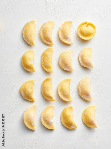The image showcases a variety of handmade dumplings beautifully arranged in rows on a clean surface