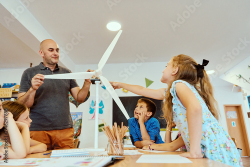 Teacher and elementary students exploring a wind turbine model during a hands-on STEM classroom lesson