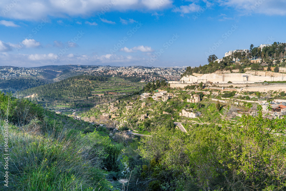 Obraz premium Panoramic view of Jerusalem neighborhoods, with the abandoned village of Lifta in the foreground, located on the slope of green hills in early spring.Israel.