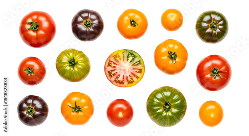 Vibrant overhead flat lay of various colorful heirloom tomatoes, including red, orange, yellow, green, and dark purple, with one sliced in half, isolated on a clean white background for fresh