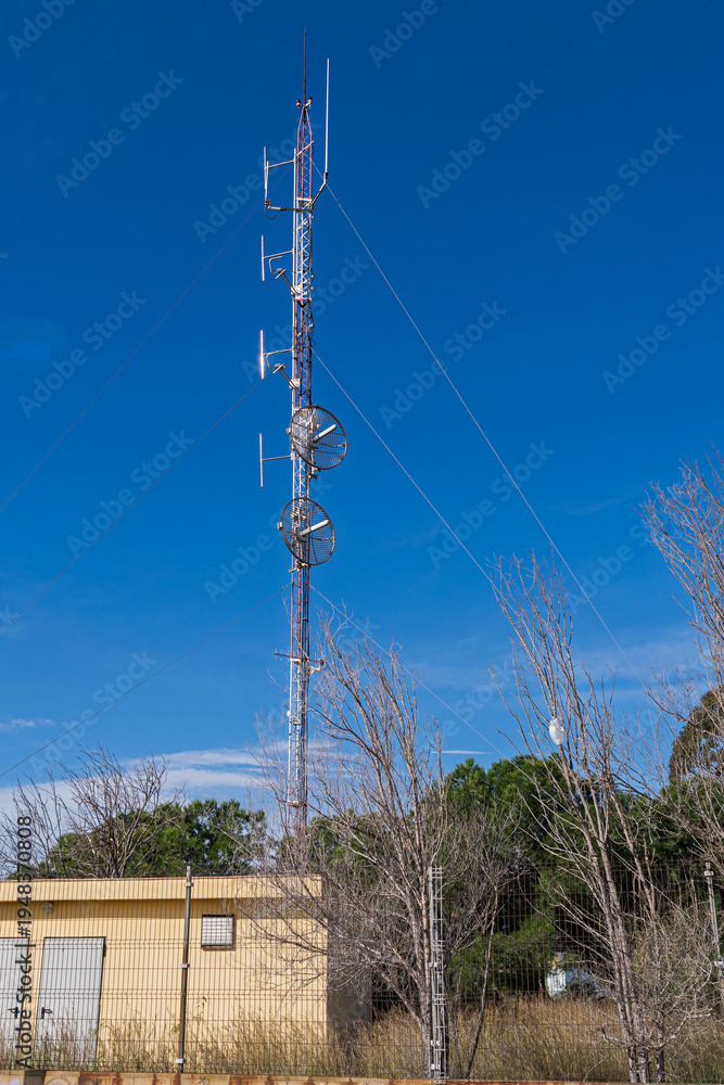 Obraz premium Telecommunications tower with parabolic antennas against clear blue sky.