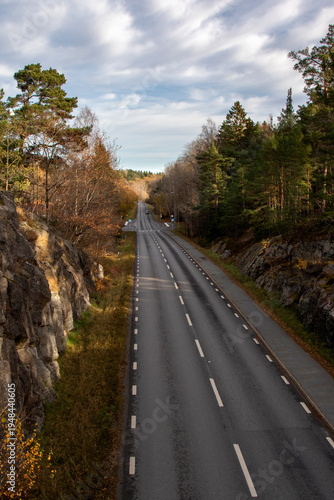 Sweden. A straight road between cliffs on an autumn day.